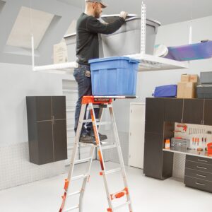 Ein Mann, der auf einer Leiter steht und auf einer Ablage eine Box abgestellt hat.